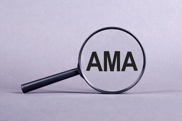 AMA - ask me anything symbol. Concept words AMA on magnifying glass paper on gray background.