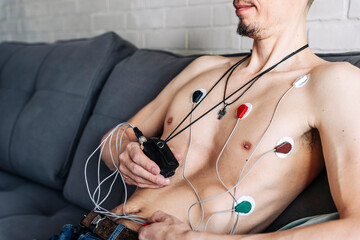 a man sitting on a sofa with a Holter heart monitor connected