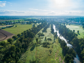 Aerial view or green grass at riverside with morning sunlight sparkling off Hunter River water