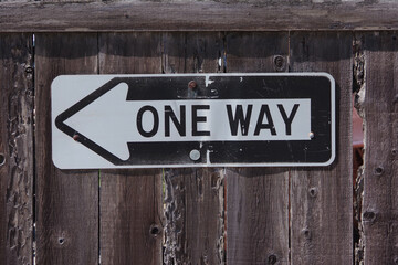 ONE WAY sign on a wood plank fence