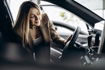 Woman choosing a car in car showroom