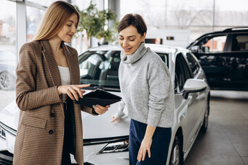 Woman in car showroom talking to salesperson