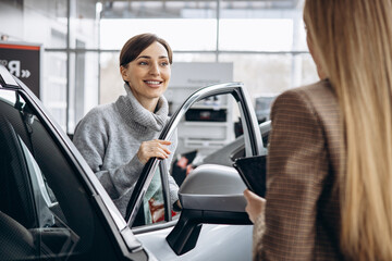 Woman in car showroom talking to salesperson