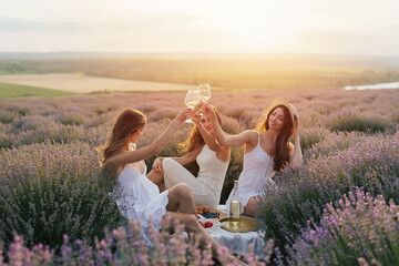 The company of female friends having fun and enjoys a summer  picnic on the lavender field and...