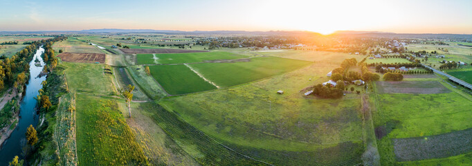 Panoramic aerial view of green farm paddocks beside Hunter River in rural NSW at sunset
