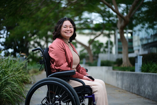 Smiling Filipina woman in wheelchair outside