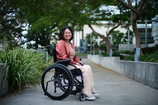 Happy woman in wheelchair on footpath