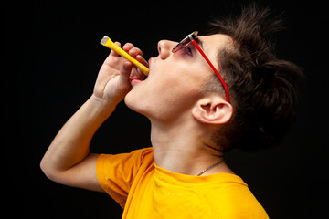 A young guy addicted to sweets, candies and sugar, pouring sugar to his mouth. Isolated on black...