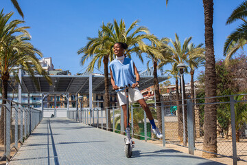 African student girl with her electric scooter enjoying in palm tree park