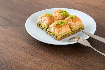 Turkish baklava with pistachio in plate.A plate baklava on wooden background,top view
