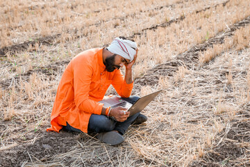 Young indian farmer in depression after see some detail in laptop.