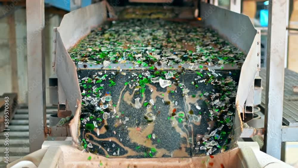 Wall mural Process of sorting glass garbage on a vibrating conveyor belt at waste sorting plant. Slow motion