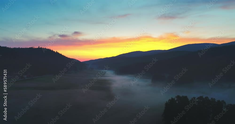 Wall mural morning dew over fresh grass on a mountain field and scenic foggy sunrise, 4k aerial video