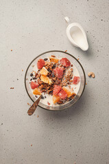 Granola (muesli) with milk, fruits (orange and grapefruit), cashew nuts and raisins. Healthy breakfast concept. Perfect for phone wallpaper, stories background, food blog post photo and so on