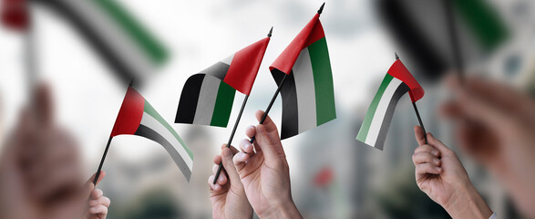 A group of people holding small flags of the Arab Emirates in their hands