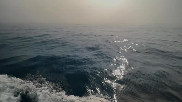 Rough and rocky wake and waves at sea in slow motion. Point of view from a ferry boat gliding through Lake Superior on an overcast foggy day.