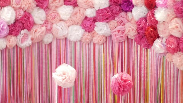 Birthday pink photo zone made of artificial paper flowers and linen. Pink photo zone for the holiday. Decoration of the room in pink.