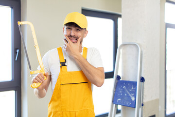 young handsome man with mouth and eyes wide open and hand on chin. handyman with a saw