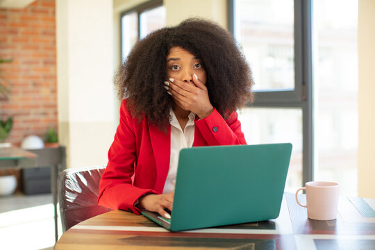 pretty afro black woman covering mouth with a hand and shocked or surprised expression. businesswoman and laptop concept
