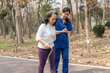 nurse helping elderly woman with walker Nurse holding hand and help elderly woman walking in park facility