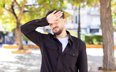 young handsome man looking stressed, tired and frustrated, drying sweat off forehead, feeling...
