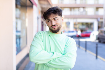 Obraz premium young handsome man feeling displeased and disappointed, looking serious, annoyed and angry with crossed arms