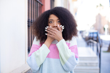 african american pretty woman covering mouth with hands with a shocked, surprised expression, keeping a secret or saying oops