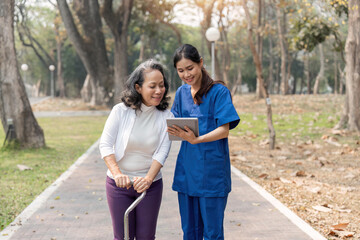 nurse caregiver showing a tablet screen to senior woman and laughing at walking in park for healthcare or nursing home