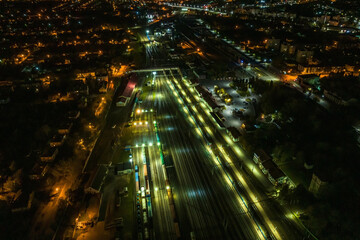 Fototapeta na wymiar night aerial view over long railway freight trains with lots of wagons stand on parking