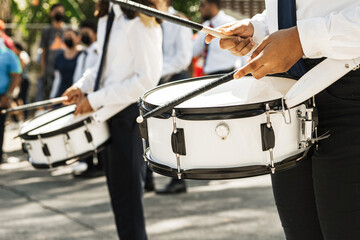 Hands of a person playing a snare with drumsticks.