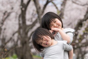 桜の咲く公園で遊ぶ姉妹