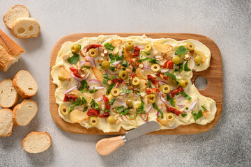 Popular Butterboard with sun-dried tomatoes, thyme, onion, garlic on gray background. View from above.