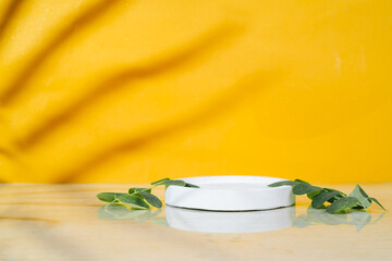 Abstract empty white podium with leaves on yellow background