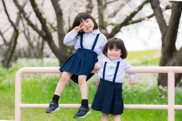 幼稚園の制服を着た姉妹と満開の桜