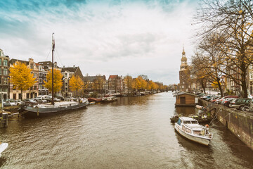 Fototapeta premium Kalkmarkt with the Montelbaanstoren with a canal at the historic old city of Amsterdam with blue sky, the Netherlands