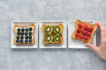 Hand taking piece of toast with fruit. Healthy eating breakfast or snack. Open faced sandwich.