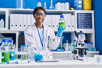 Young african american woman scientist measuring liquid at laboratory