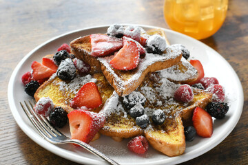 Plate of French toast topped with berries and powdered sugar, breakfast brunch