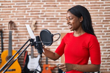 Fototapeta na wymiar Young african american woman artist singing song at music studio