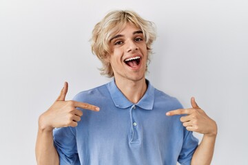 Young modern man standing over isolated background looking confident with smile on face, pointing...