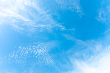 Summer bright blue sky with sunlight and natural white clouds. Copy space in the middle.