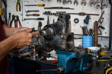 Mecánico reparando pieza de un motor en su taller