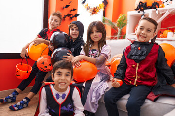 Group of kids wearing halloween costume holding balloons at home