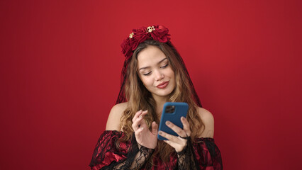 Young beautiful hispanic woman wearing katrina costume using smartphone over isolated red background