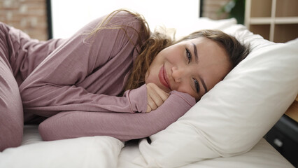 Young beautiful hispanic woman smiling confident lying on bed at bedroom