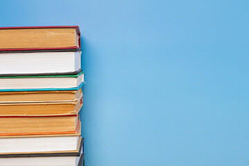 Stack of books in the colored cover lay on blue backround. Education learning concept