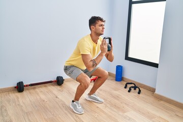 Young hispanic man using kettlebell training at sport center