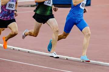 Fototapeta premium three runners athletes on middle distance running together in track stadium, summer athletics championship