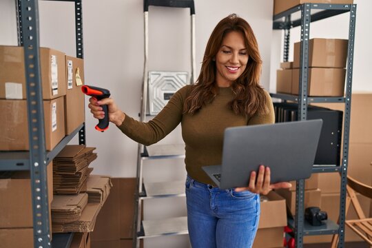 Young latin woman business worker scanning package using barcode reader at office