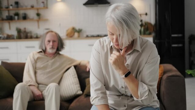 problems in family relationships in an elderly couple, family crisis. An elderly couple in a living room sit without talking to each other, holding a grudge